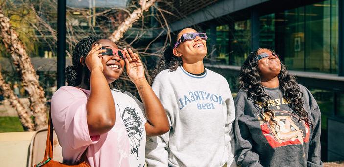 三个学生戴着日食眼镜看太阳.